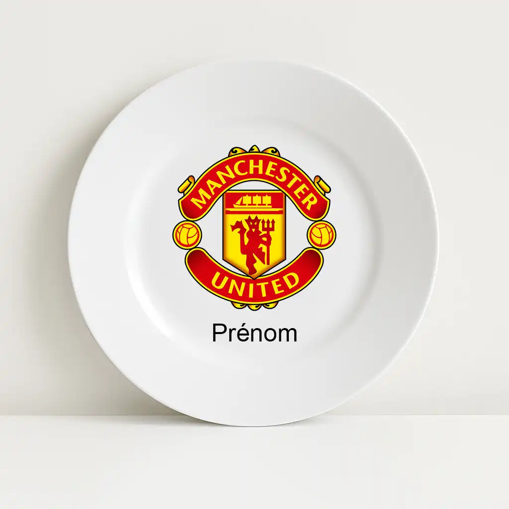 Assiette blanche avec le logo du club de football Manchester United au centre, surmontant l’inscription personnalisable "Prénom".