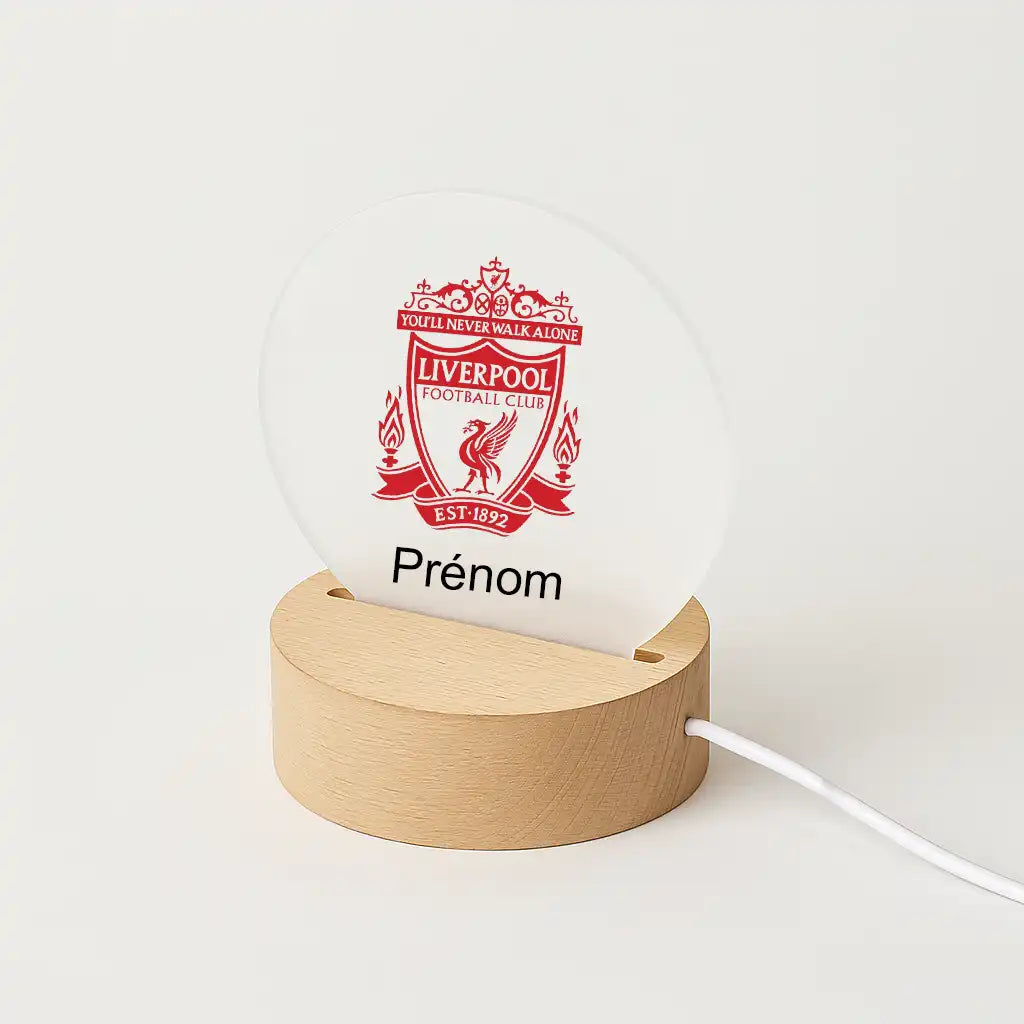 Lampe LED personnalisable avec le logo de Liverpool, posée sur une base en bois clair, avec l'inscription "Prénom" sous l'écusson du club.