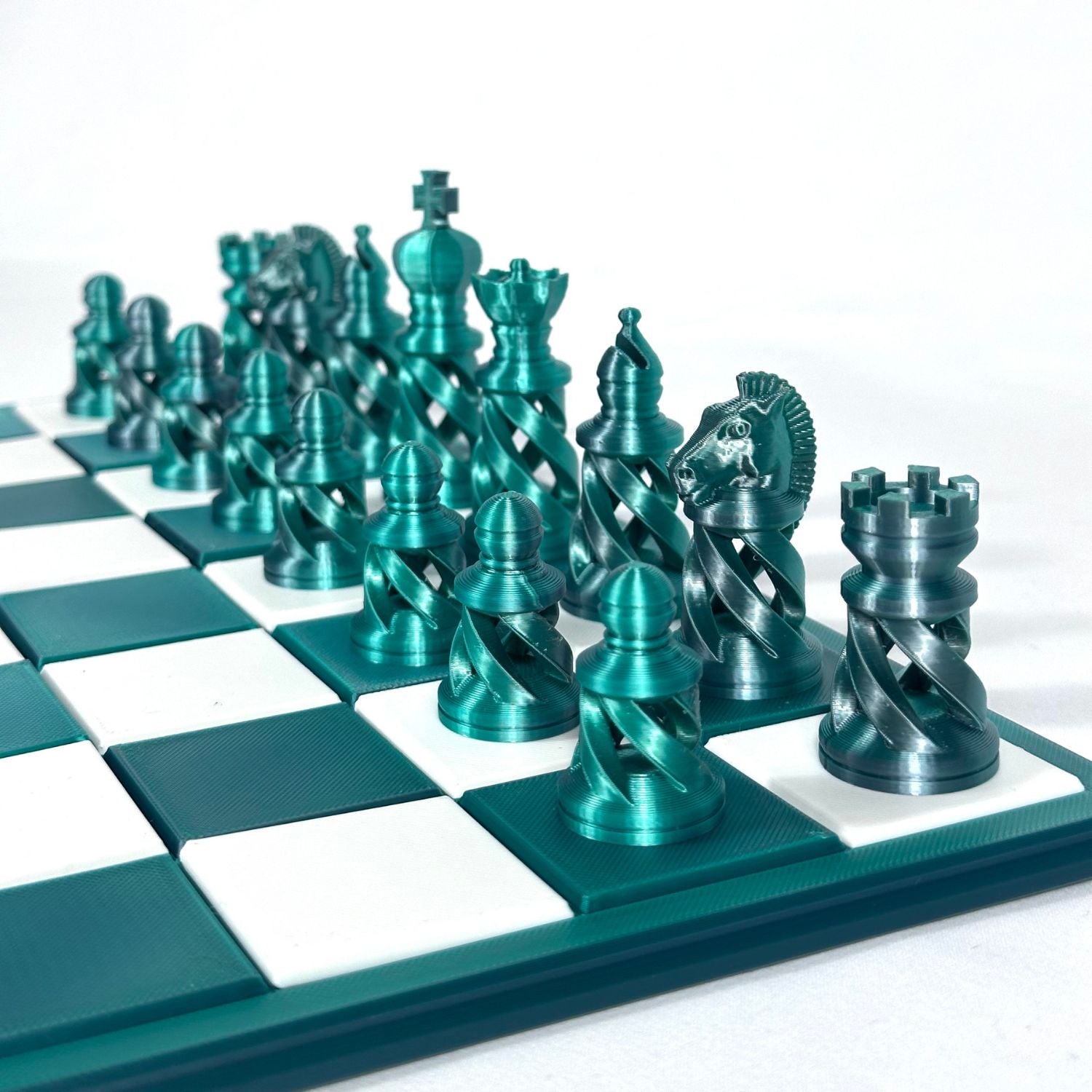 Set d’échecs design spiralé avec pièces métalliques couleur jade et chrome, sur échiquier moderne haut de gamme.