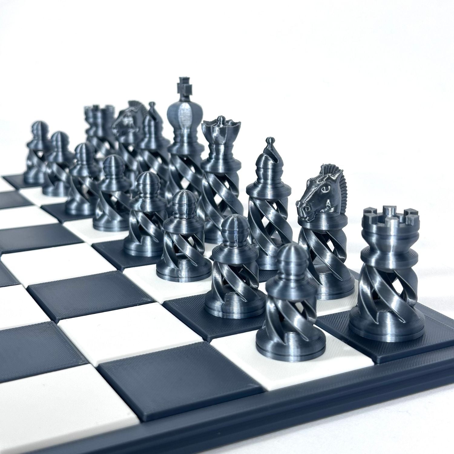 Zoom sur pièces d’échecs contemporaines effet acier, incluant roi, dame et fou, posées sur échiquier moderne luxe.