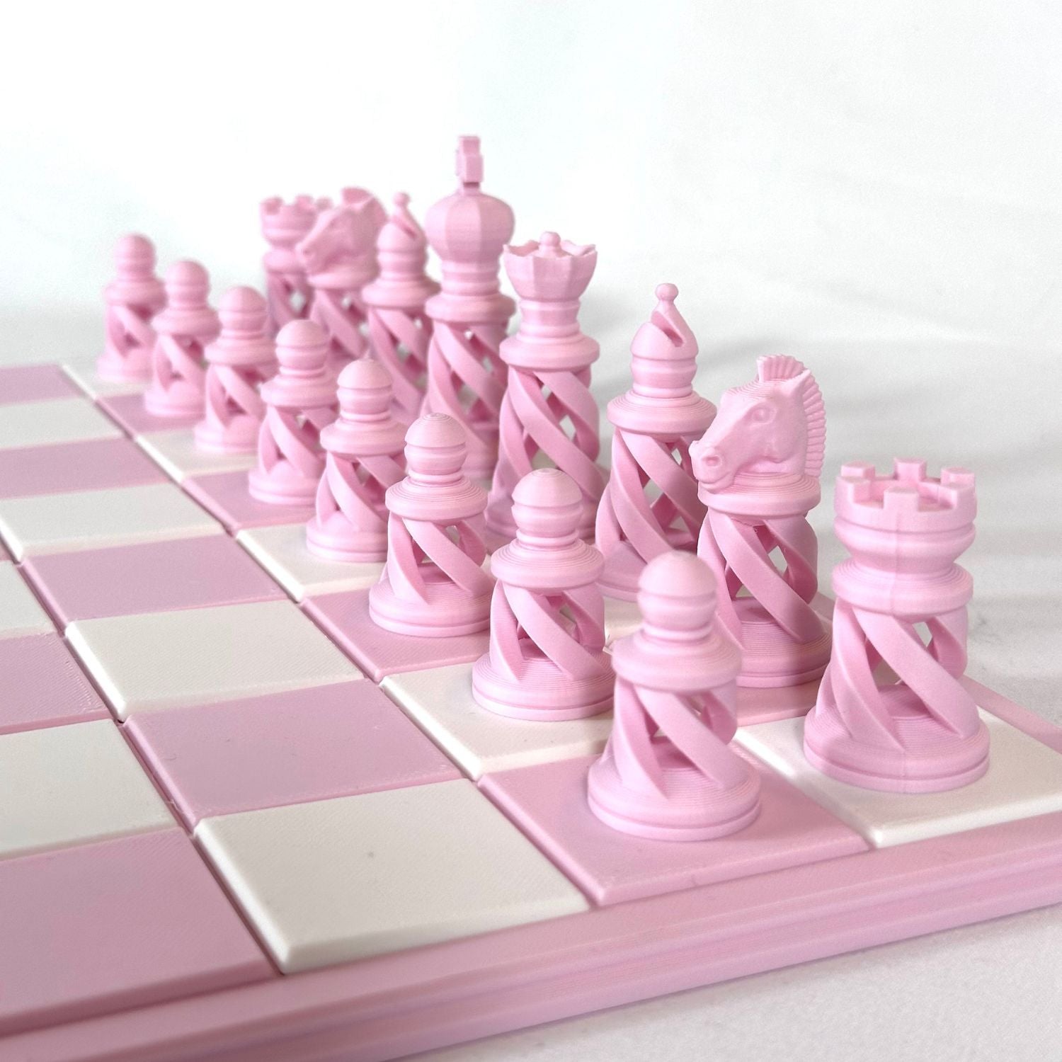 Ensemble complet de pièces d’échecs modernes rose pastel sur échiquier rose et blanc