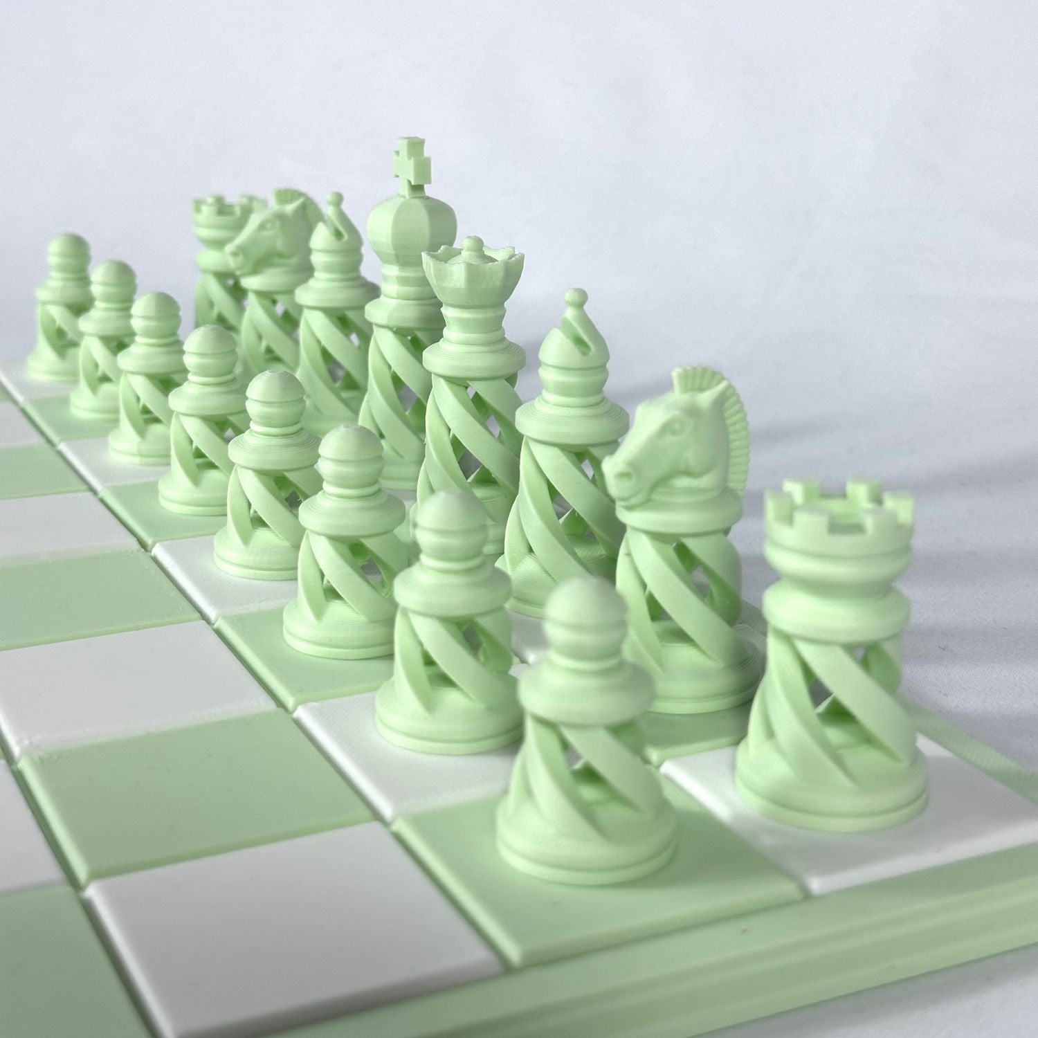 Ensemble complet de pièces d’échecs modernes vert pastel sur échiquier vert et blanc
