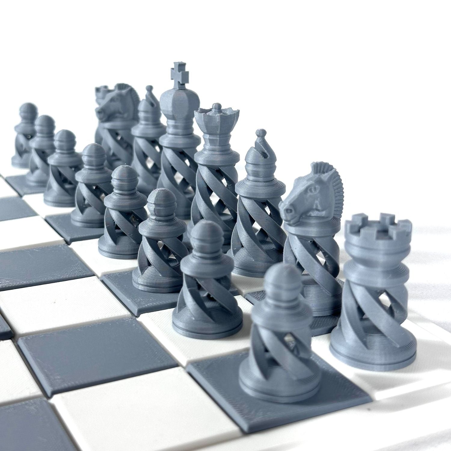 Zoom sur pièces d’échecs design moderne gris, impression 3D haute qualité sur plateau contrasté.