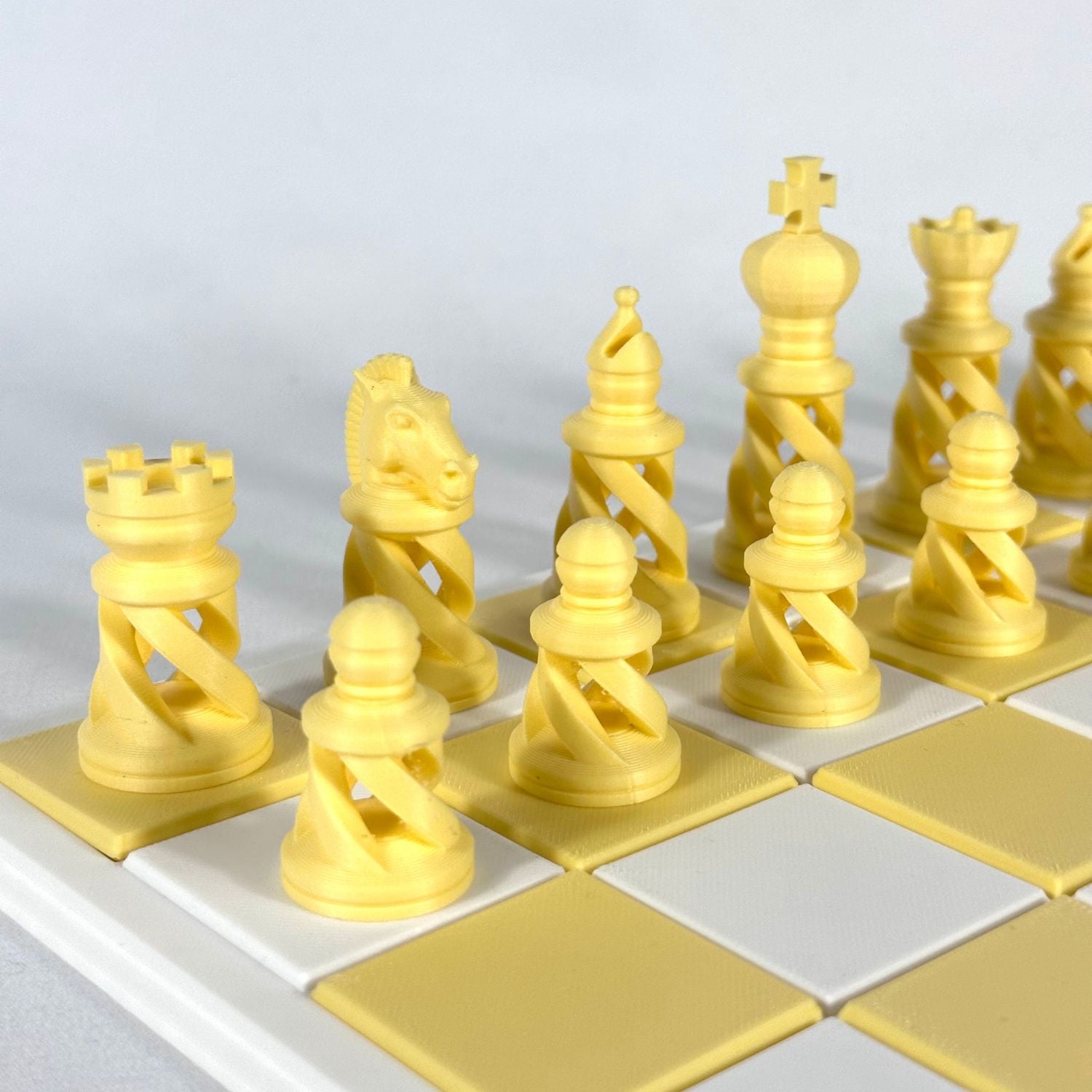Pièces d’échecs modernes spiralées couleur jaune pastel sur échiquier blanc et jaune clair, impression 3D.