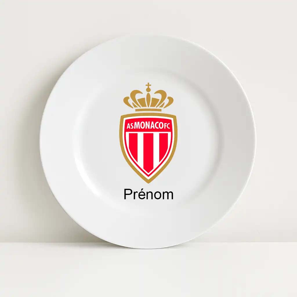 Assiette blanche incassable arborant fièrement le blason officiel du club de football AS Monaco, centré sur la surface. En dessous du logo, l'inscription “Prénom” permet la personnalisation au nom de l’enfant ou du supporter.