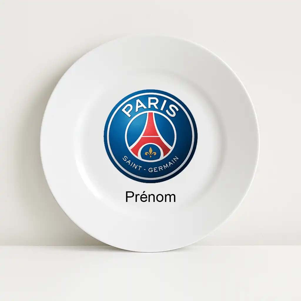 Assiette blanche incassable personnalisable avec le logo officiel du Paris Saint-Germain (PSG) au centre. Le blason rond bleu, rouge et blanc arbore la tour Eiffel stylisée avec une fleur de lys en dessous. Le mot "Prénom" figure sous le logo pour personnalisation.