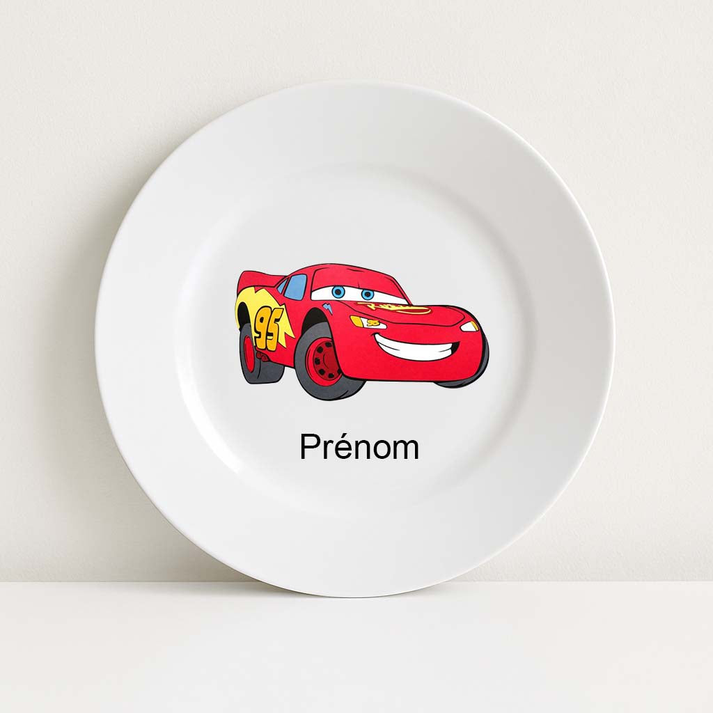 Assiette blanche incassable avec une illustration colorée du personnage Flash McQueen (Cars) au centre, accompagnée du mot “Prénom” en dessous pour personnalisation.