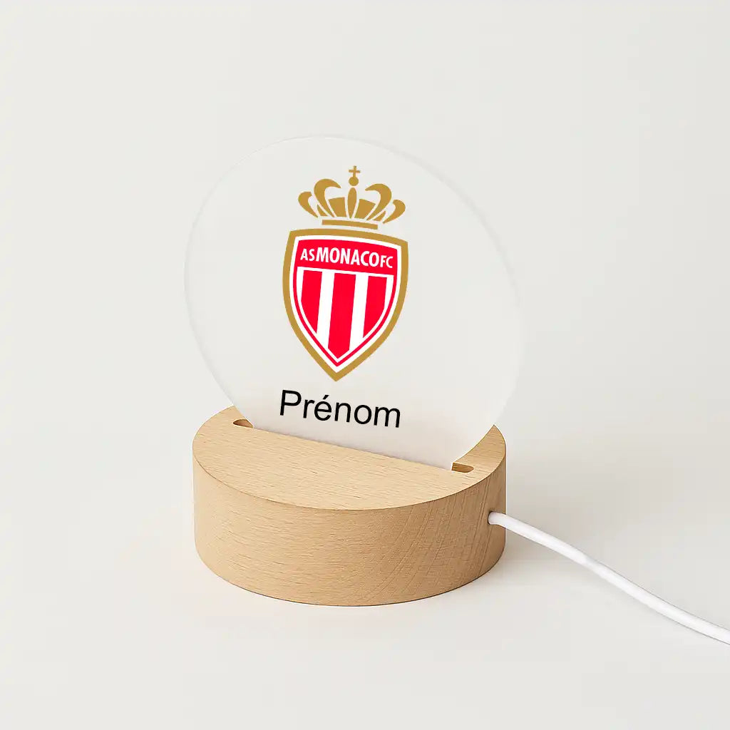 Lampe LED personnalisable avec le logo de L'AS Monaco, posée sur une base en bois clair, avec l'inscription "Prénom" sous l'écusson du club.