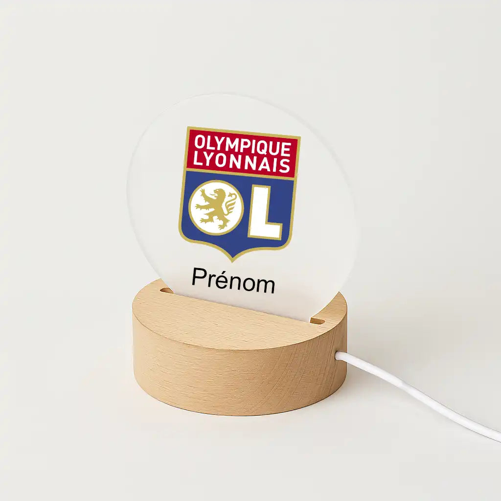 Lampe LED personnalisable avec le logo de l'omlypique Lyonnais, posée sur une base en bois clair, avec l'inscription "Prénom" sous l'écusson du club.
