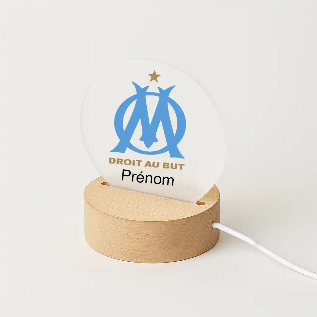 Lampe LED personnalisable avec le logo de l'olympique de Marseille, posée sur une base en bois clair, avec l'inscription "Prénom" sous l'écusson du club.