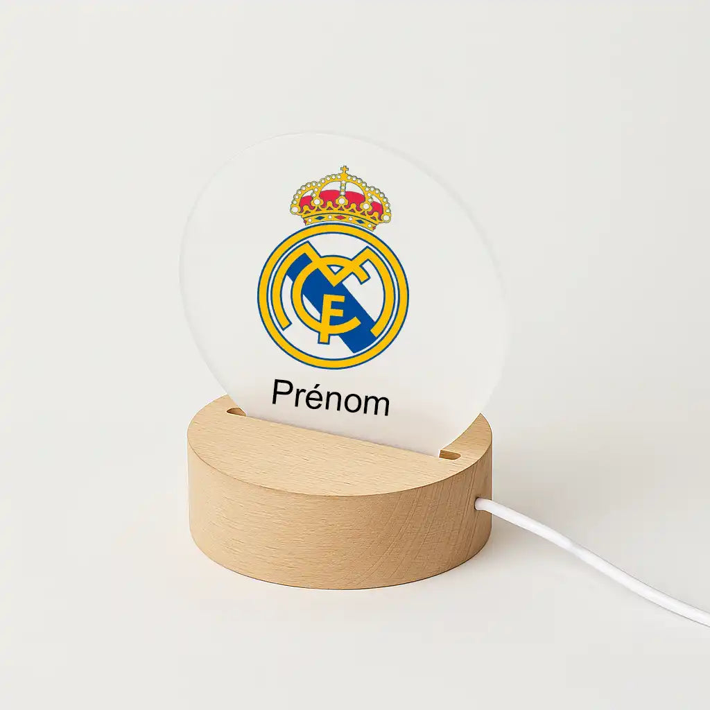 Lampe LED personnalisable avec le logo du Real Madrid, posée sur une base en bois clair, avec l'inscription "Prénom" sous l'écusson du club.