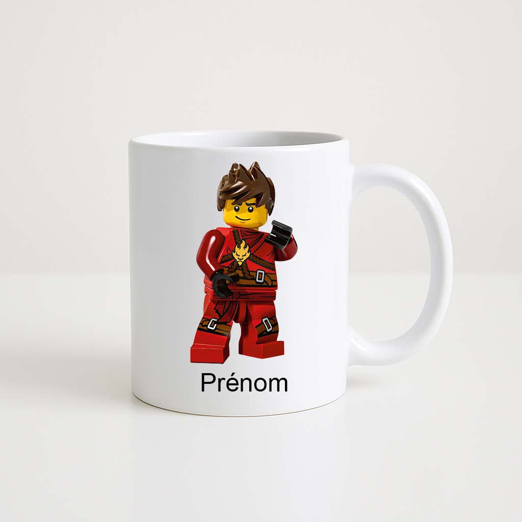 Mug blanc 330 ml avec figurine Lego ninja en tenue rouge et visage souriant, personnalisable avec un prénom.
