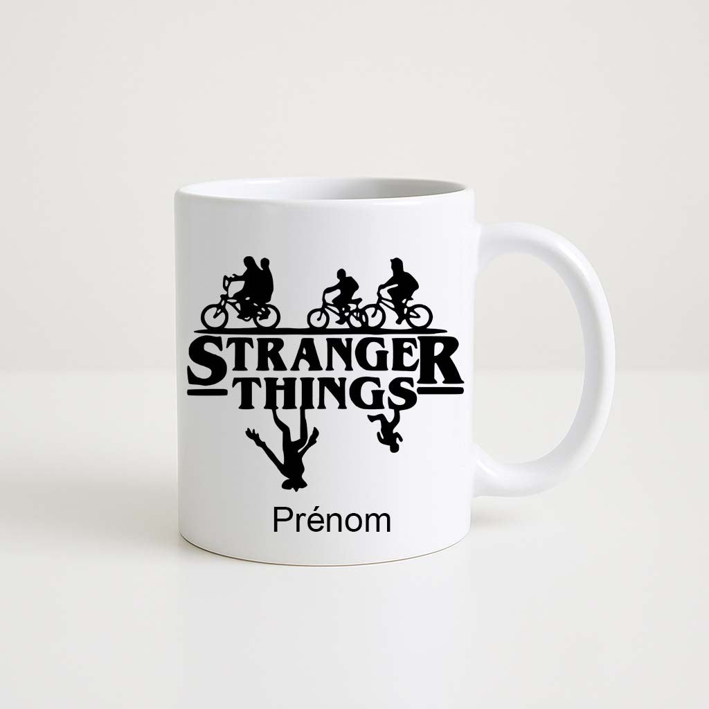Mug blanc 330 ml avec logo Stranger Things noir, silhouettes d’enfants à vélo et monstres inversés, espace personnalisable pour prénom