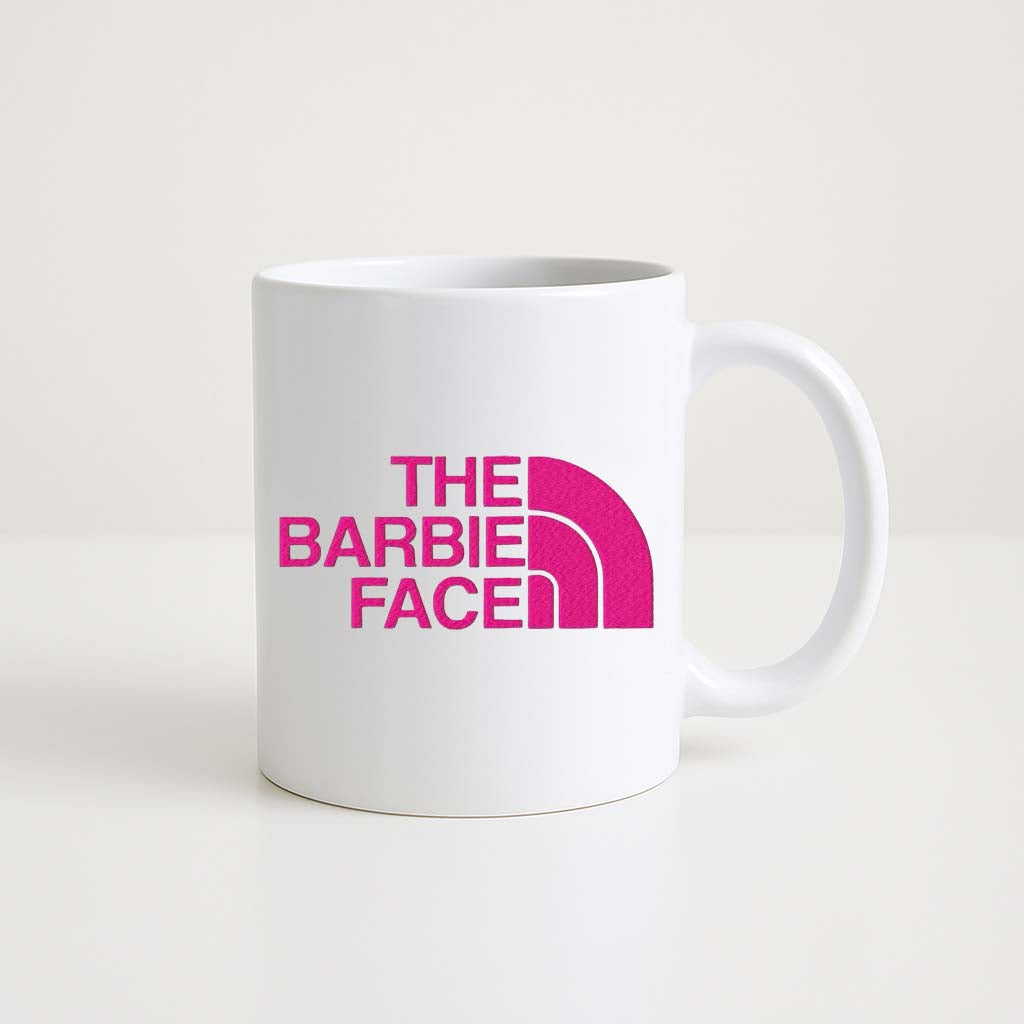 Mug blanc 330 ml avec texte rose « The Barbie Face » et logo semi-circulaire stylisé