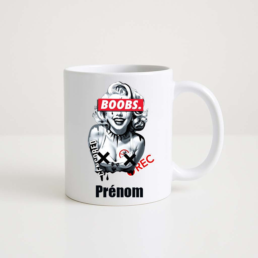 Mug blanc 330ml avec portrait stylisé Marilyn Monroe, bandeau "BOOBS.", motifs censored, espace pour un prénom personnalisable.