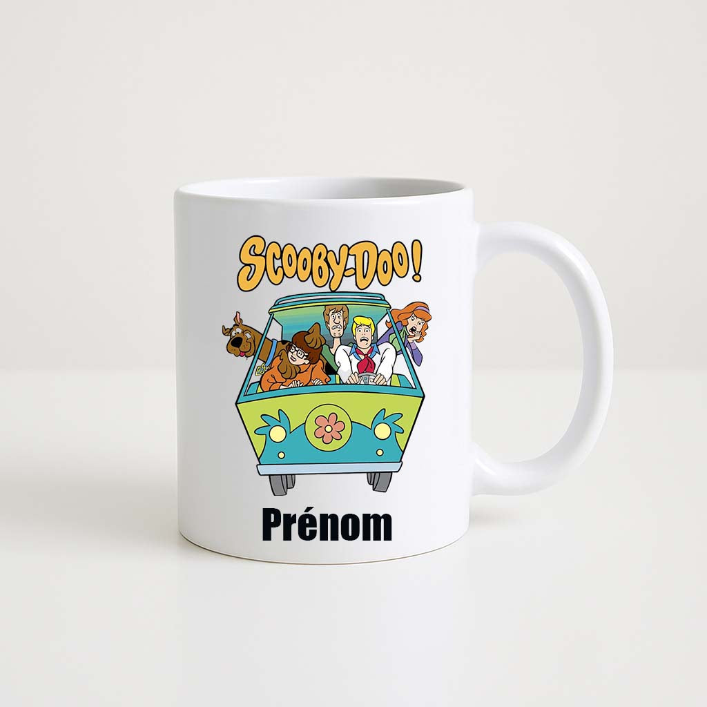 Mug blanc 330ml avec le van Mystery Machine, Scooby-Doo, Salsbury, Fred, Daphné et Véra à l’intérieur, espace pour un prénom personnalisable.