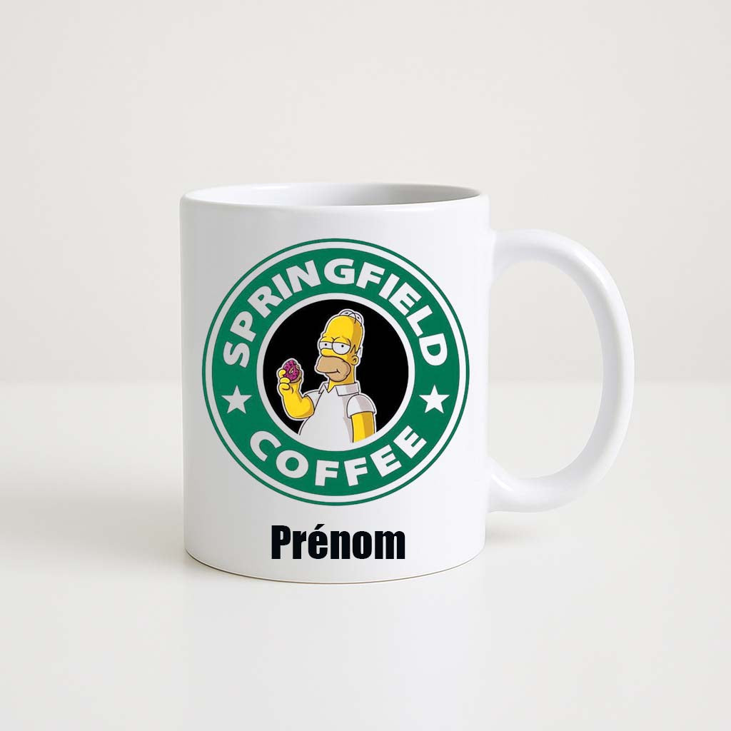 Mug blanc 330ml avec Homer Simpson tenant une tasse de café, décor Springfield, espace pour un prénom personnalisable.