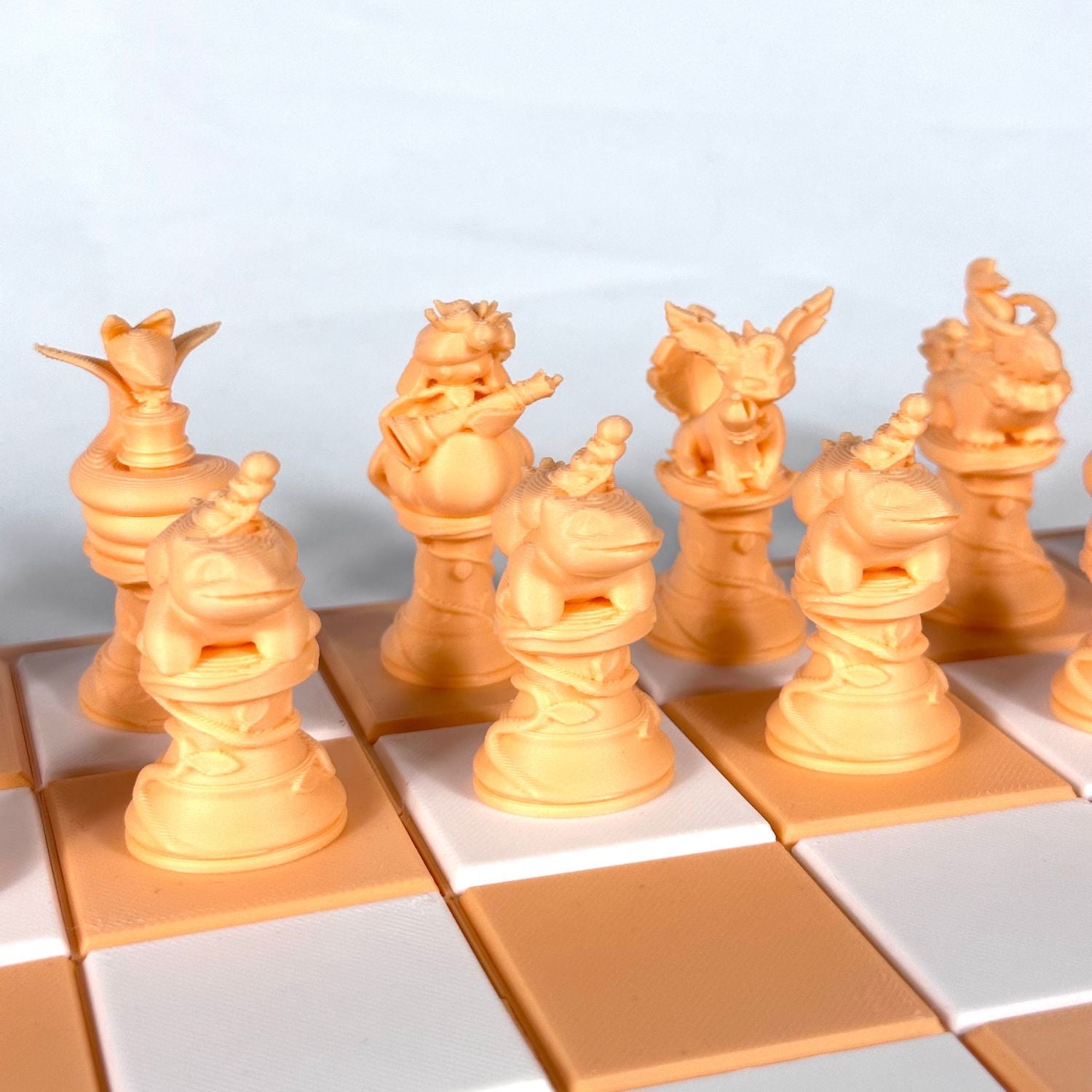 Gros plan sur les pièces d’échecs Pokémon pêche pastel au design détaillé et artisanal, sans plateau.