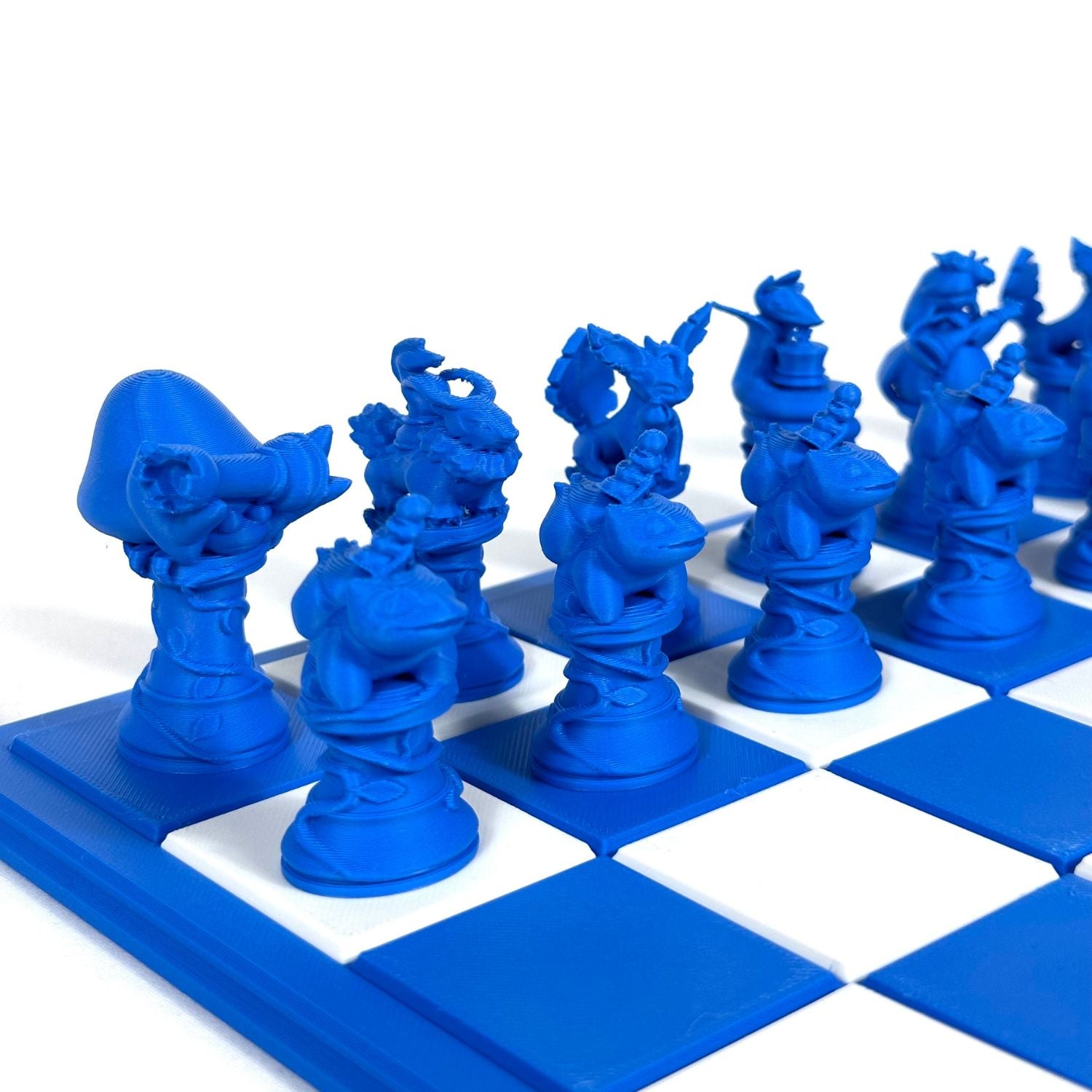 Pièces d’échecs inspirées Pokémon en bleu saphir, imprimées en 3D et alignées sur un échiquier bleu et blanc.