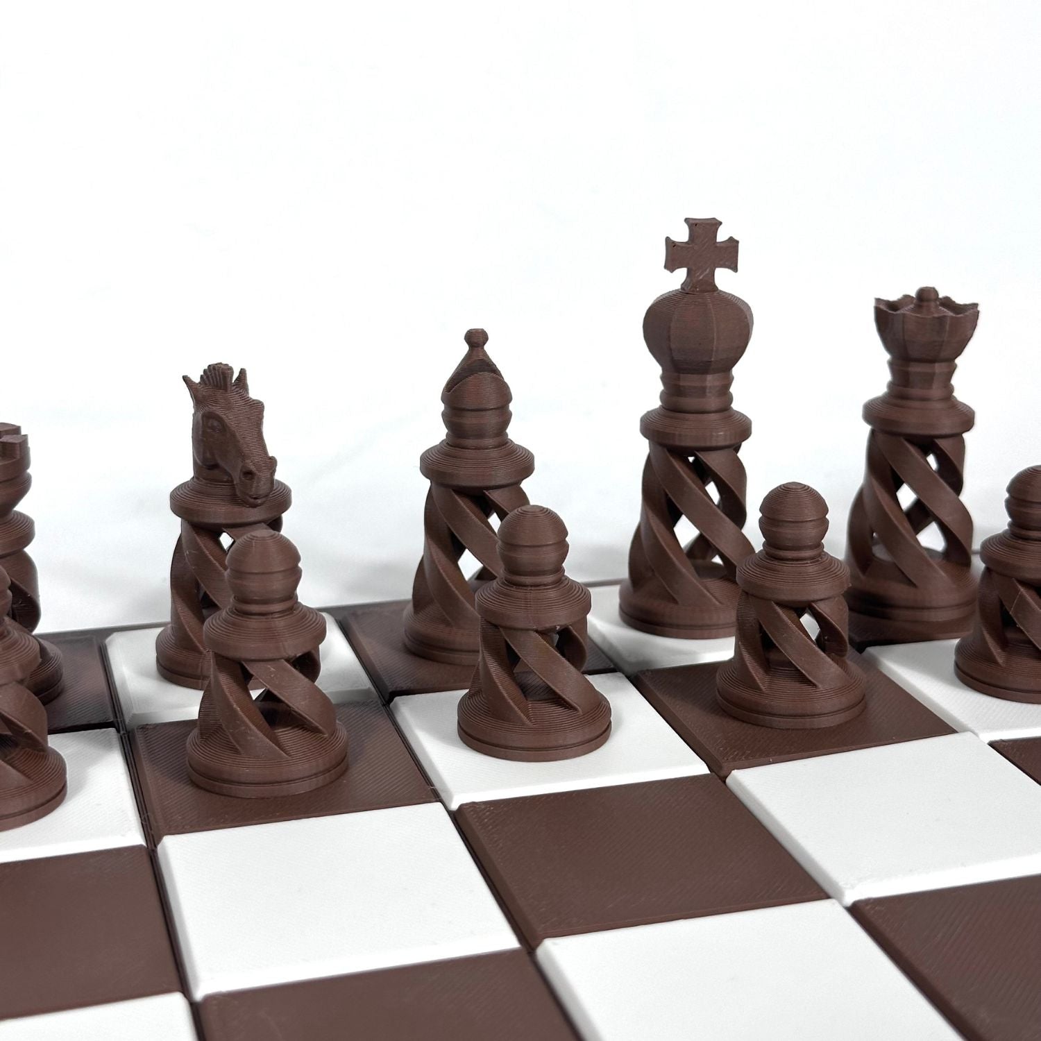 Set d’échecs marron chocolat au style ajouré contemporain, aligné sur un plateau quadrillé marron et blanc.