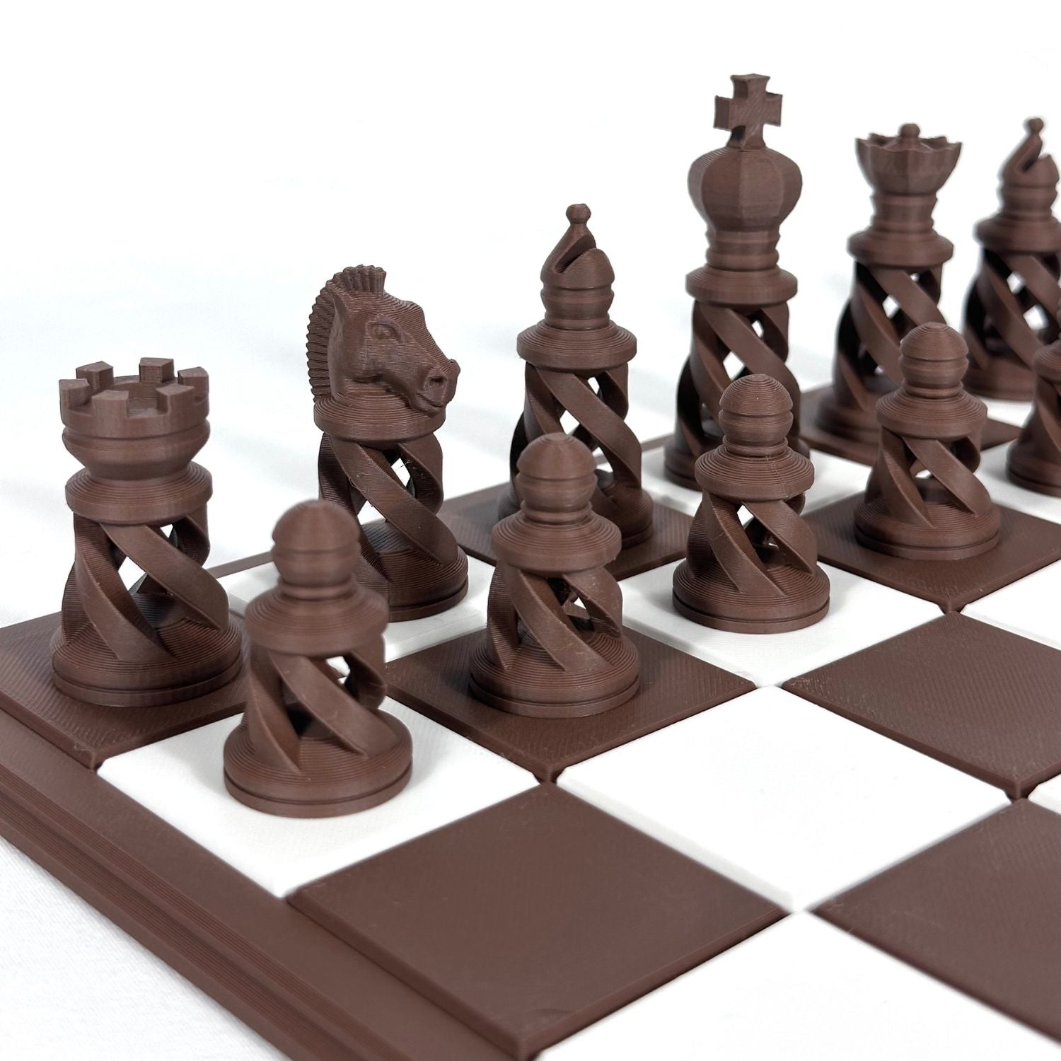 Pièces d’échecs modernes marron imprimées en 3D avec design ajouré, disposées sur un échiquier marron et blanc.