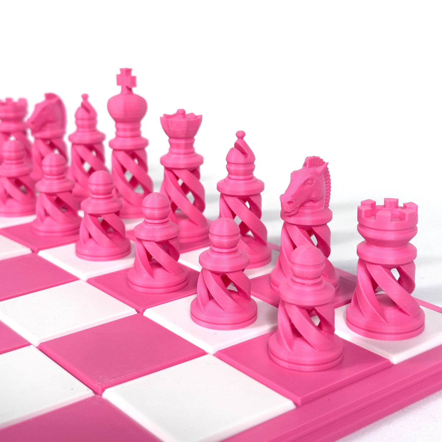 Pièces d’échecs roses au design ajouré contemporain, imprimées en 3D et placées sur un échiquier rose et blanc.