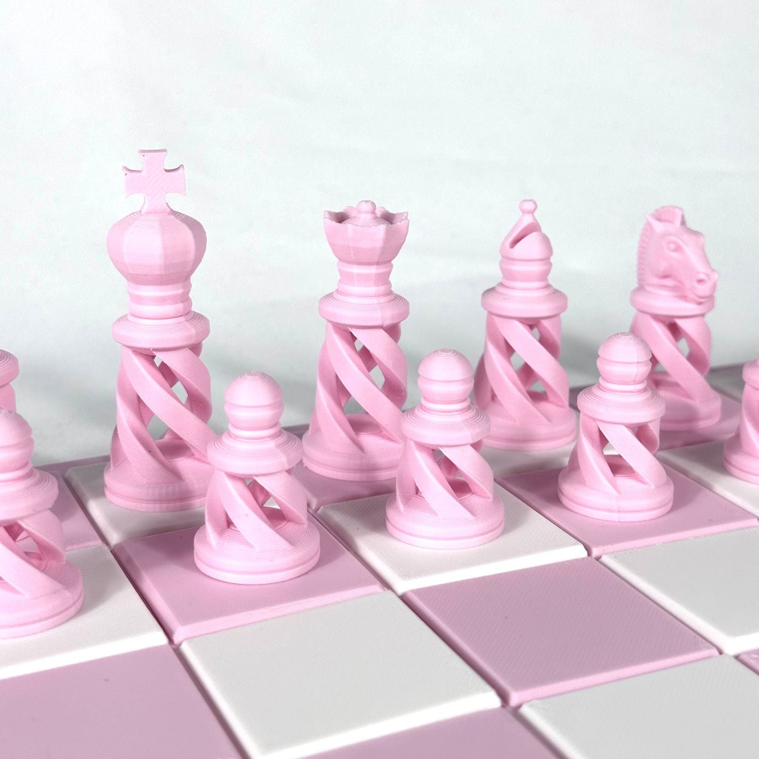Gros plan sur les pièces d’échecs modernes rose pastel au design spiralé et minimaliste – HomeDesign74.