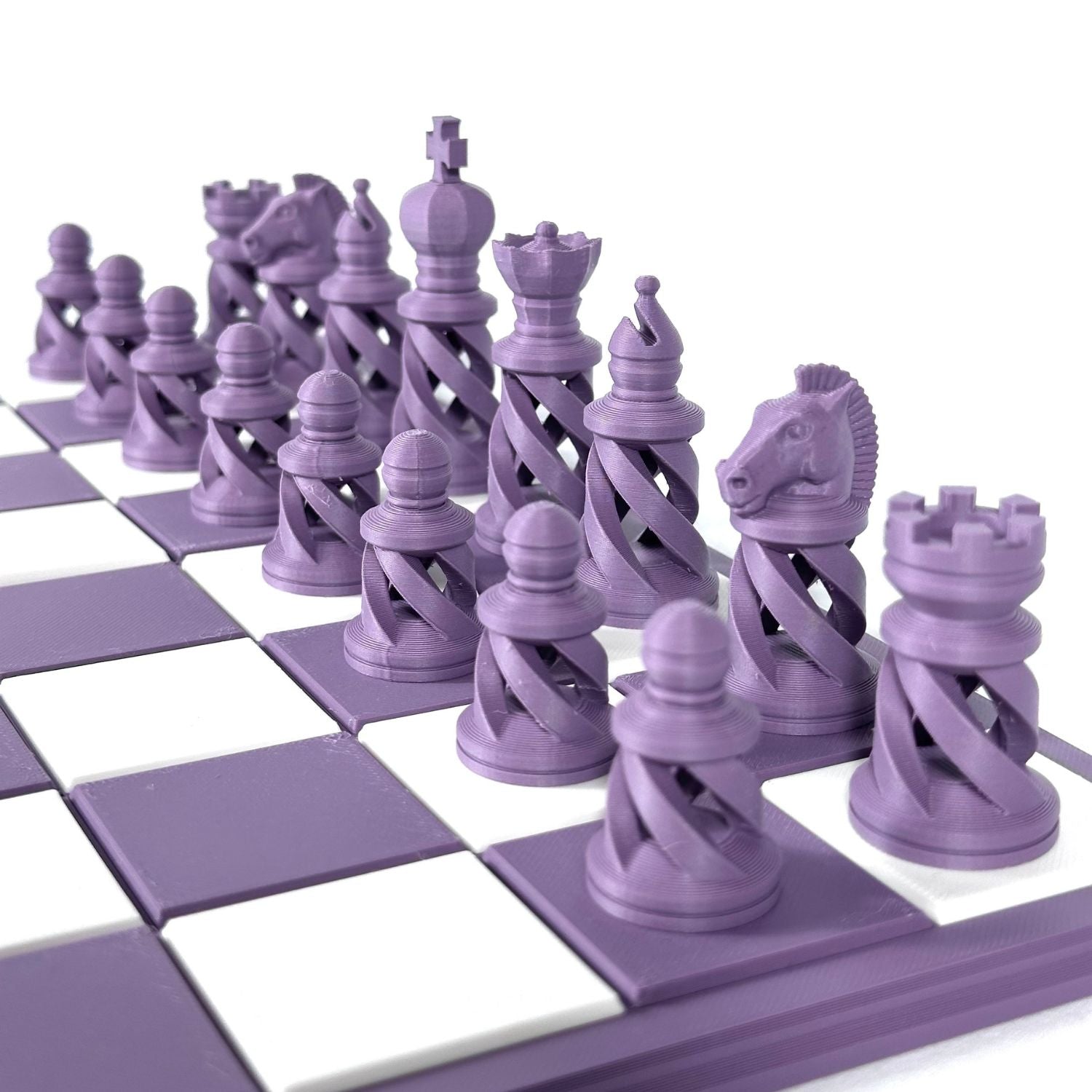 Ensemble complet de pièces d’échecs modernes couleur violet pastel disposées sur un échiquier violet et blanc