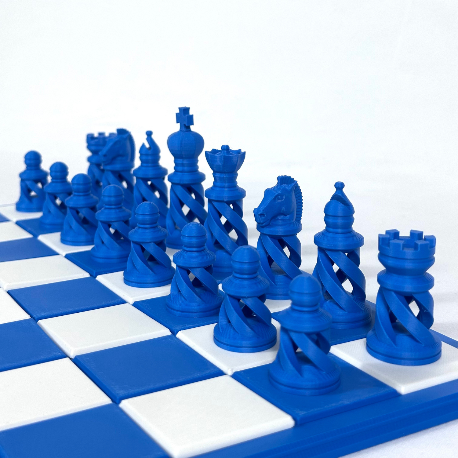 Set complet de pièces d’échecs design spiralé bleu intense, positionné sur échiquier contrasté.