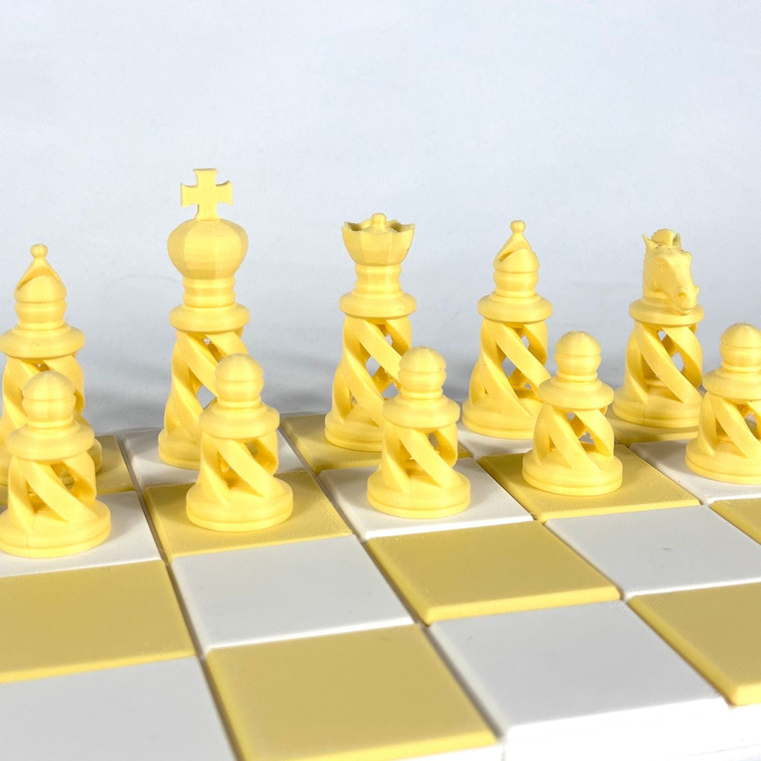 Zoom sur pièces d’échecs design contemporain jaune, incluant roi, dame et fou, sur plateau minimaliste.
