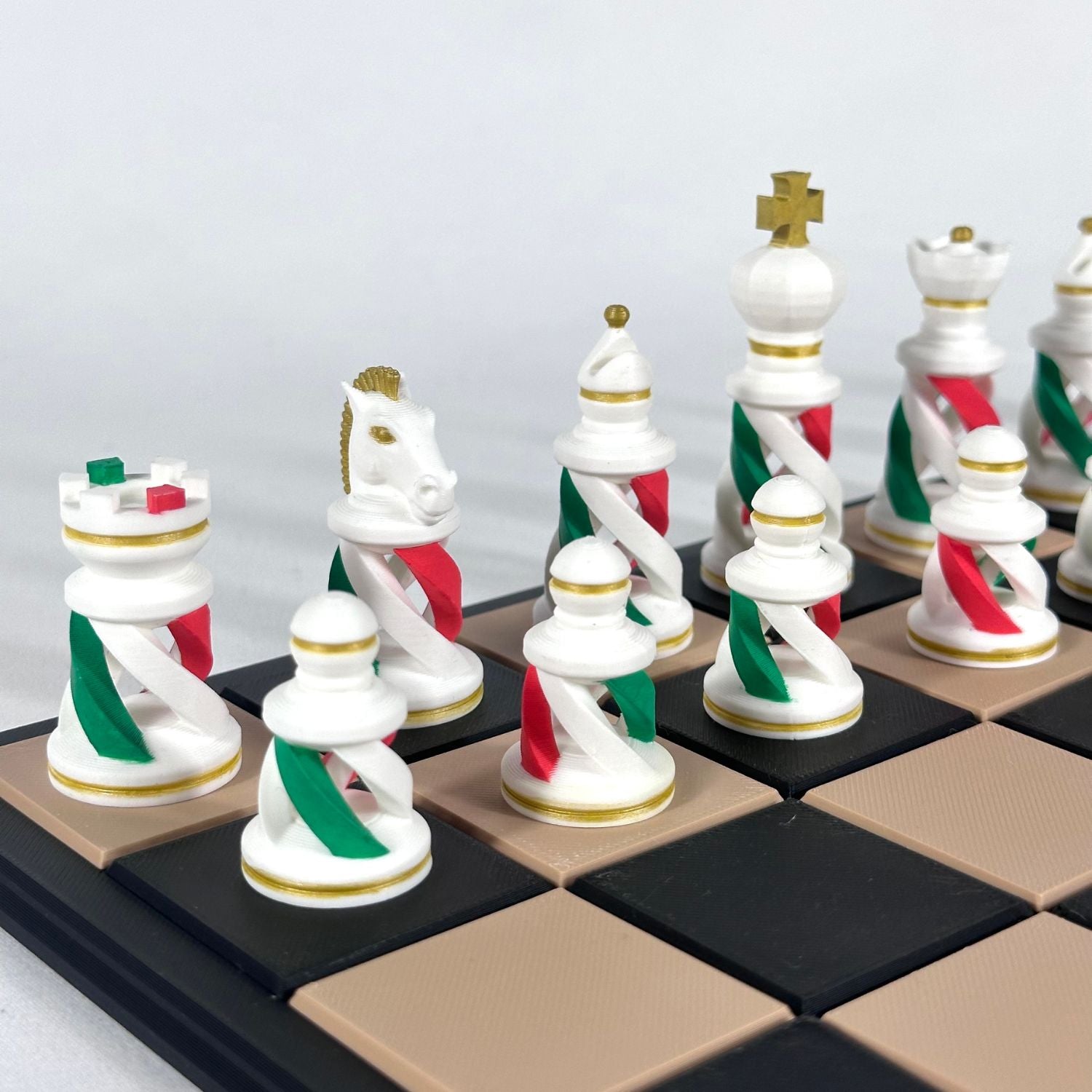 Pièces d’échecs modernes aux couleurs de l’Italie, design spiralé blanc, rouge et vert avec finitions dorées sur échiquier beige et noir.