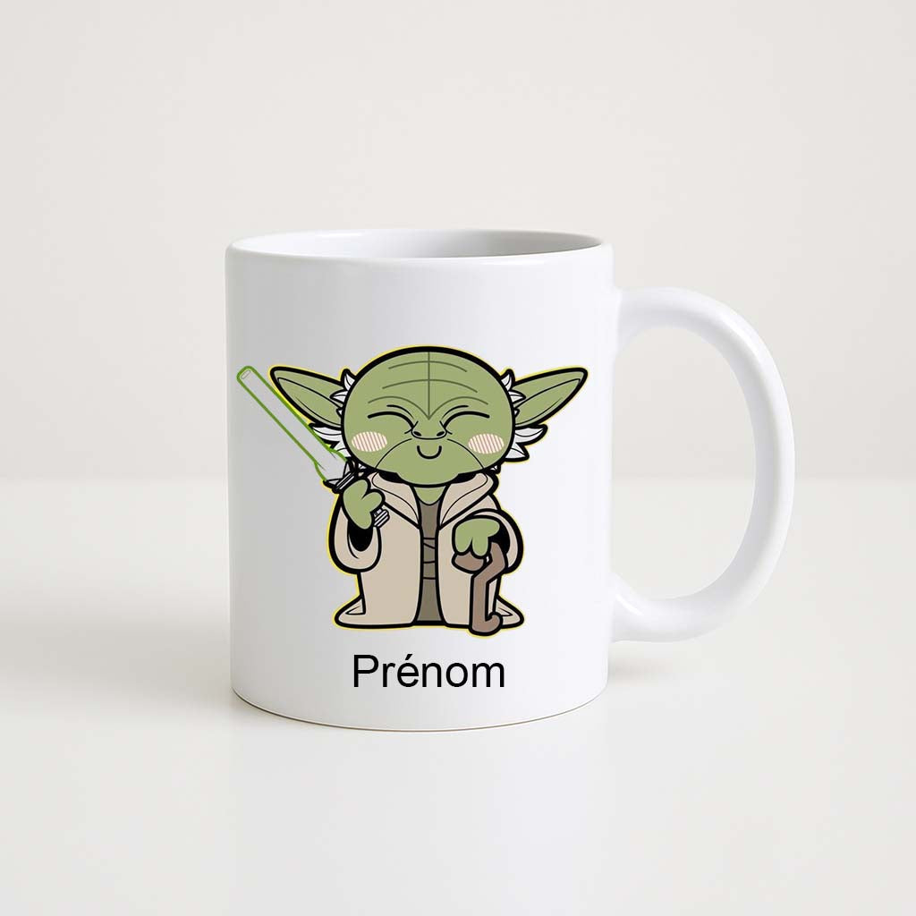 Mug blanc 330 ml avec illustration d’un personnage ressemblant à Maître Yoda en version chibi tenant un sabre laser, et espace personnalisable pour prénom